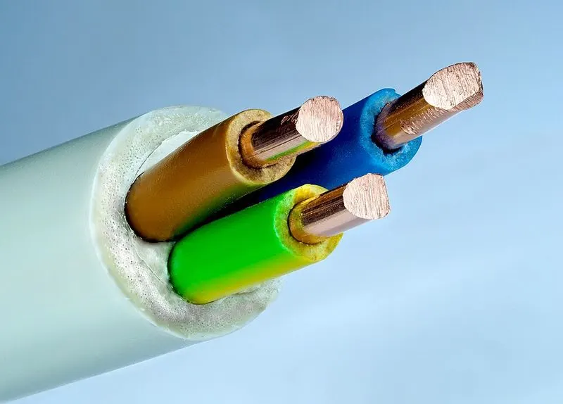 The cut end of an electrical cable with three copper wires in coloured plastic