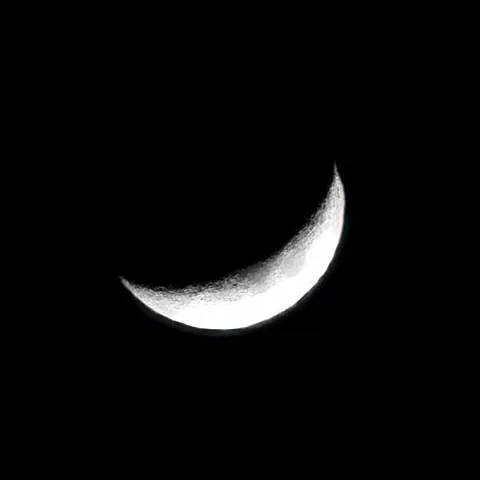 A thin crescent Moon in a dark sky