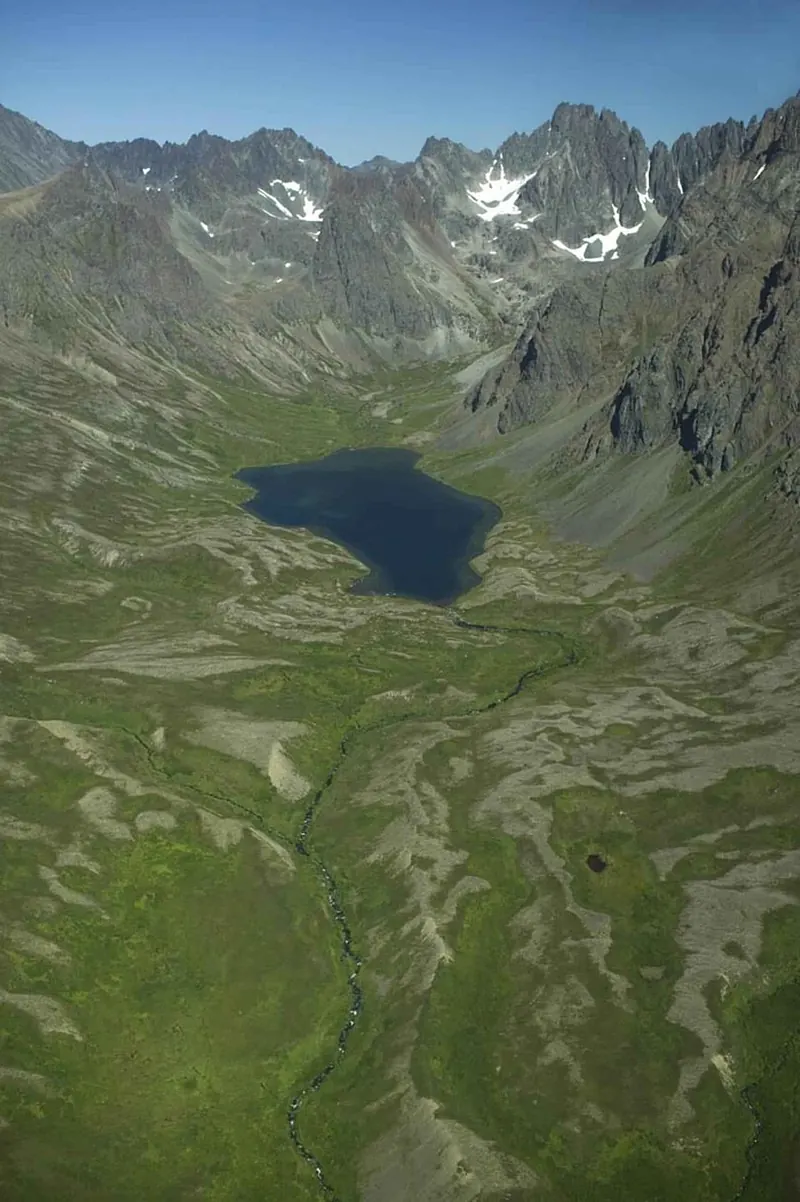 A wide U-shaped mountain valley with a lake, seen from the air
