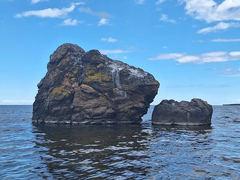 A large boulder standing in shallow sea water
