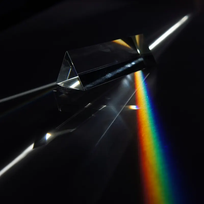 A glass prism splitting a beam of white light into a band of colours