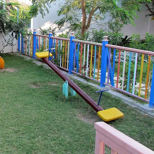 A playground seesaw with a yellow seat at each end and a pivot in the middle