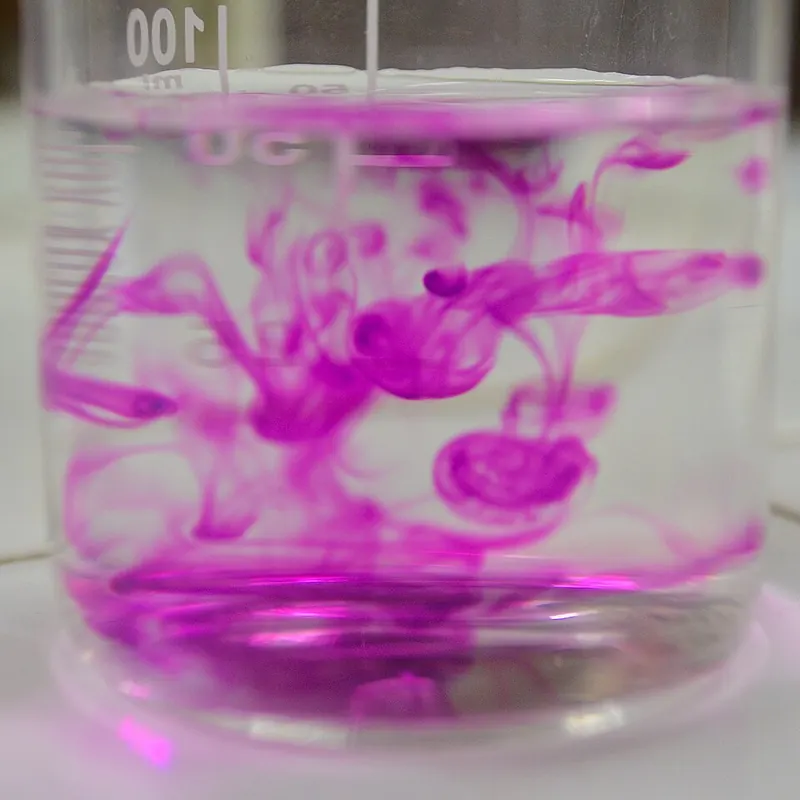 Purple potassium permanganate spreading through water in a beaker