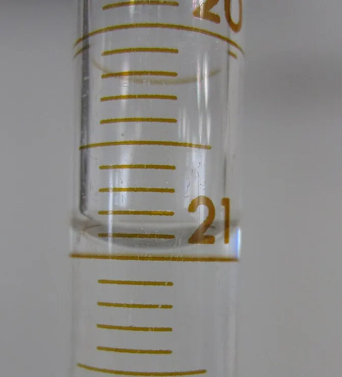 Close-up of water in a glass burette showing a curved meniscus